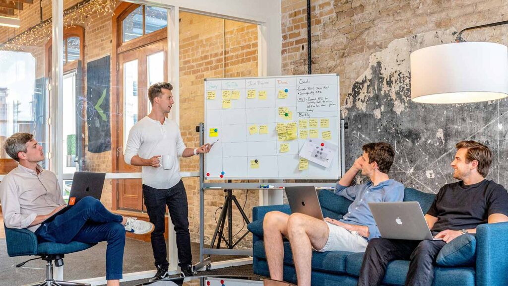 a man standing in front of a whiteboard with a man pointing at it encumbrance