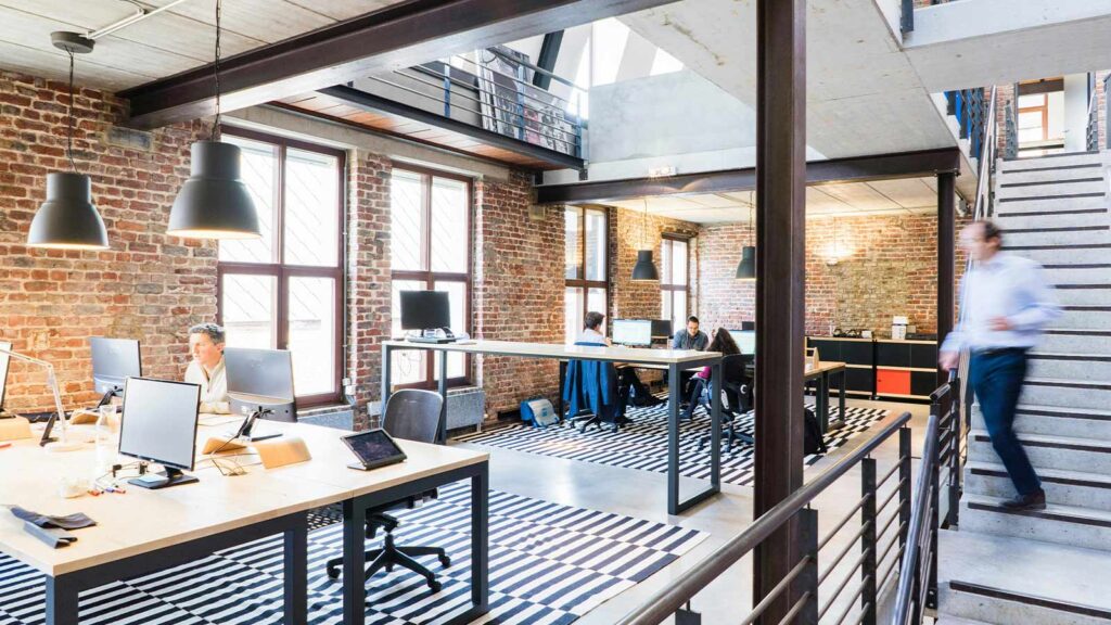 a group of people sitting at desks in a room with brick walls webhooks