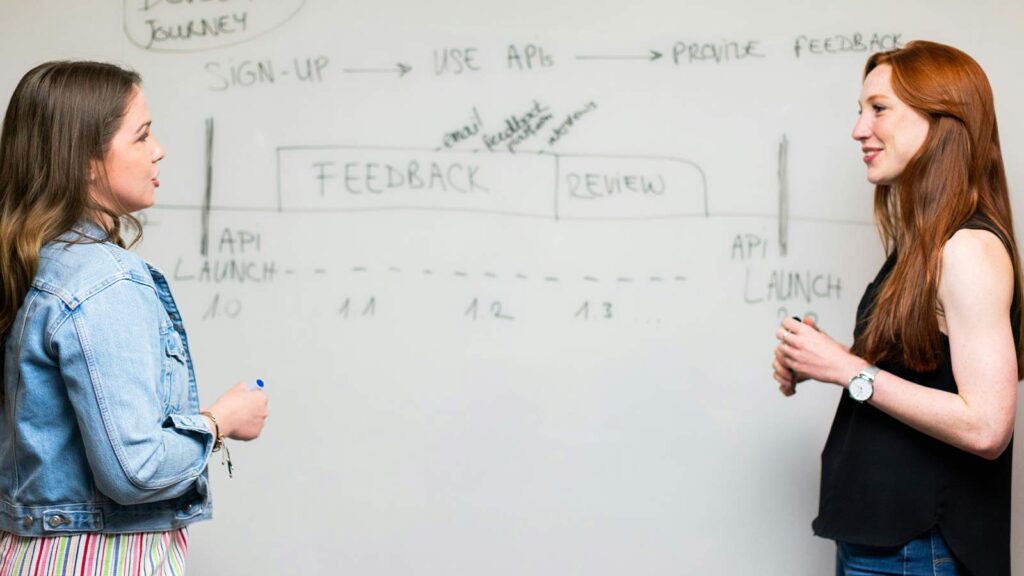 a man and woman writing on a whiteboard JSON