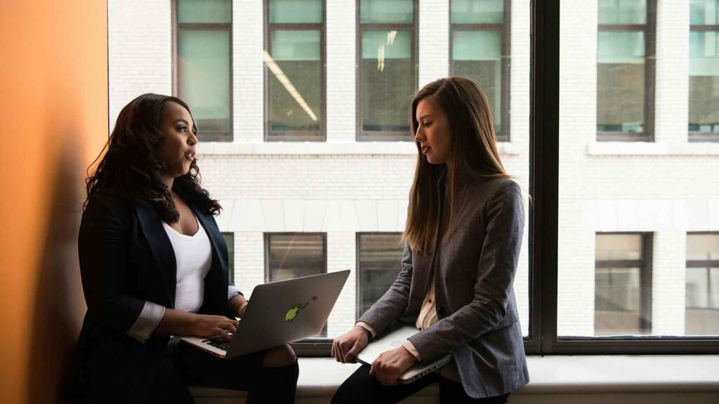 a woman sitting next to another woman Title Search for Lenders