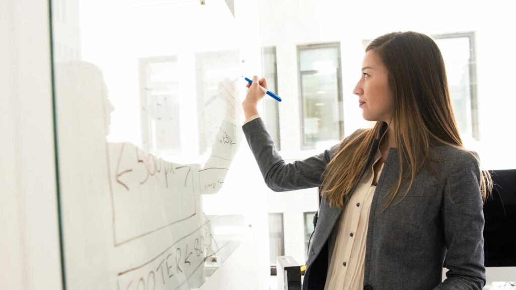 a woman writing on a glass board Title Report