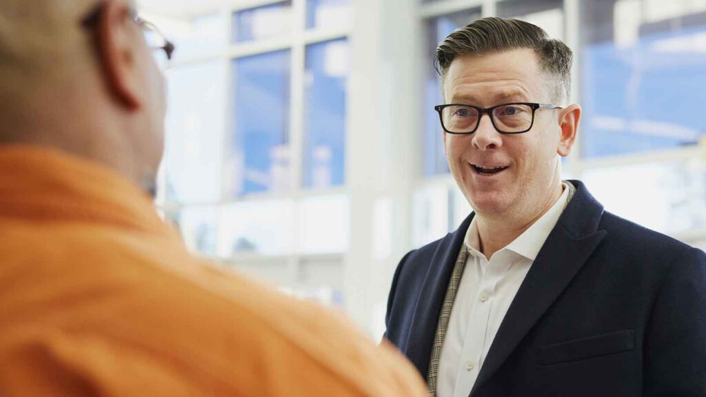 a man in a suit and glasses talking to another man Real Estate Due Diligence