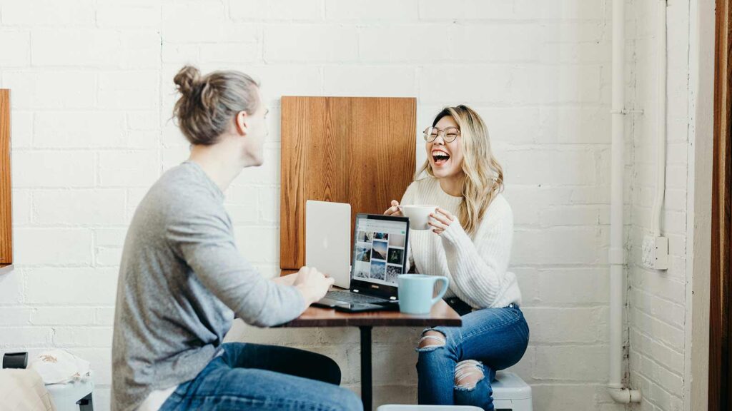 a woman laughing at a man sitting at a table with a laptop Nationwide AI Title Search
