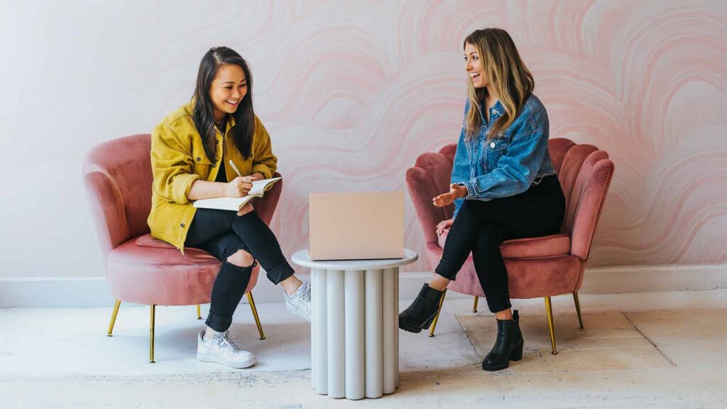 two women sitting in chairs and talking Rising-Interest-Rates