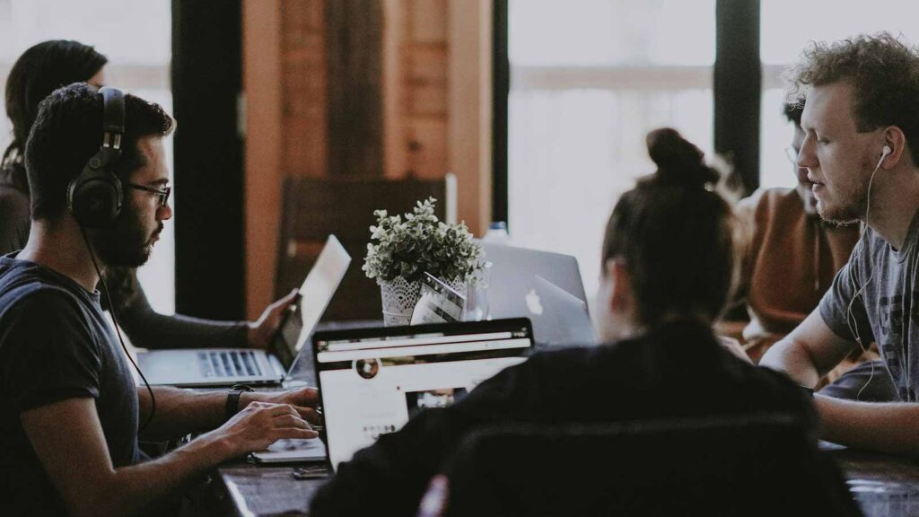 a group of people sitting at a table with laptops automated title examination