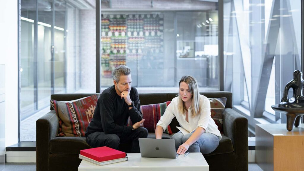 a man and woman sitting on a couch looking at a laptop same day title updates